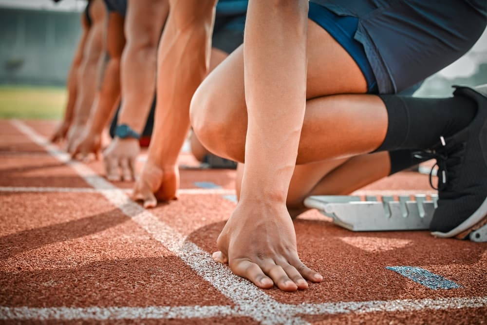 Race, start and hands of runners on track at arena for speed challenge, marathon event.