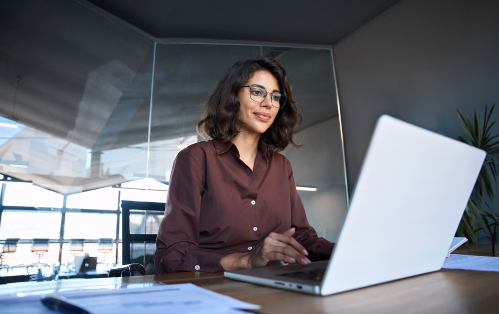 woman in office typing on a laptop looking amused