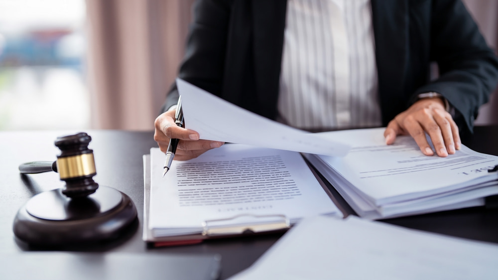 business person looking through a stack of paperwork, judge's gavel on the desk