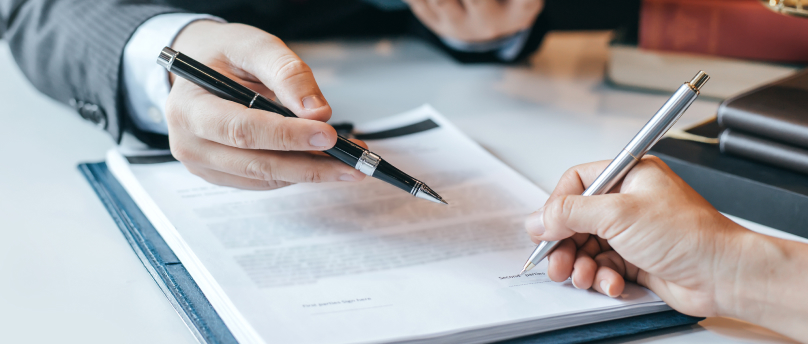 close up of hand signing prenuptial agreement papers