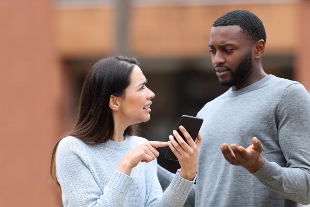 Disgusted woman asking for explanation about mobile phone text to her husband in the street.