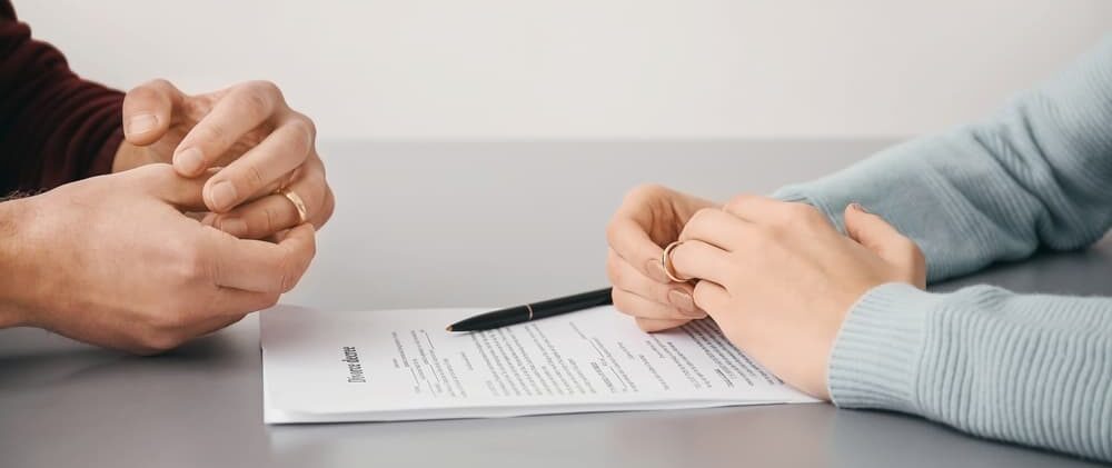 Two individuals engaged in signing a contract on a table, exploring annulment and divorce in Michigan.